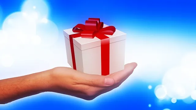 A woman's hand holding a white box tied up with a red bow 