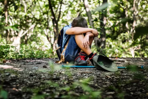 Boy lost and sad sitting alone in forest