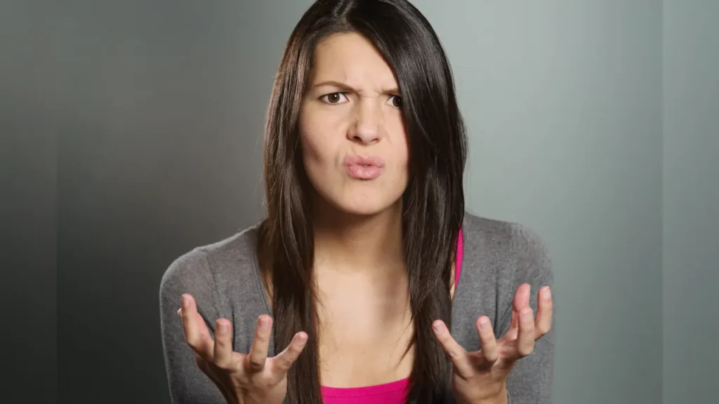 A young woman with a horrified expression clenching her hands in frustration