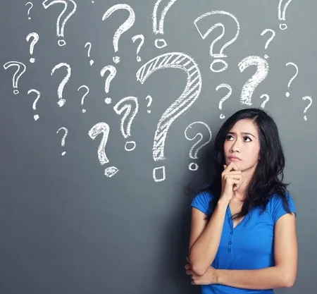 A woman stands in thought, surrounded by large chalkboard with several question marks. Each question represents the uncertainties we face.